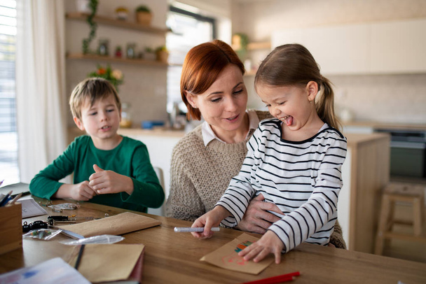 Mother of little children supervising them when diong homework at home. - Foto, Bild