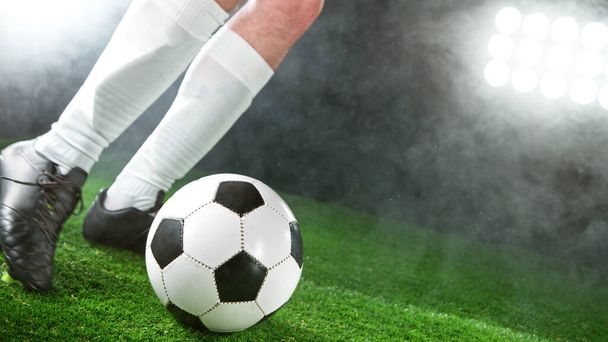 Soccer player kicking ball on grass, detailed shot. Soccer background. - Фото, изображение