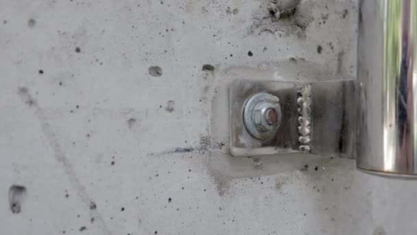 コンクリート壁マクロクローズアップストック映像でボルト。コンクリート壁にボルトでクロムメッキ手すりパイプを締結します。ボルトは他のボルトの横にコンクリートにねじ込みます。灰色の金属. - 映像、動画