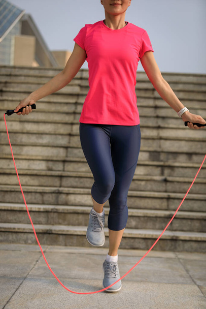 Fitness woman jumping rope in city - Fotó, kép