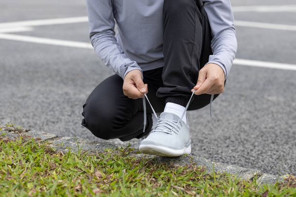 Healthy lifestyle sporty asian woman tying shoelace running at tropical park - Photo, Image