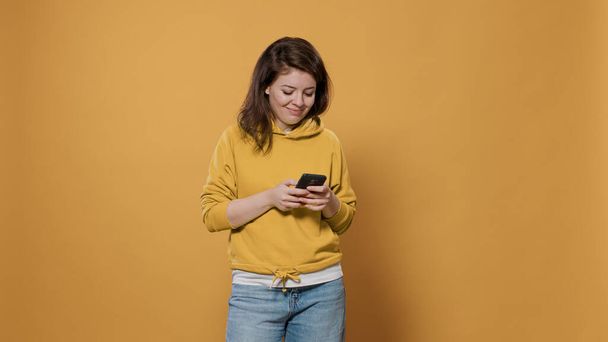 Portret niezobowiązującej kobiety trzymającej SMS-a na smartfonie, mającej urzekającą rozmowę online w mediach społecznościowych - Zdjęcie, obraz