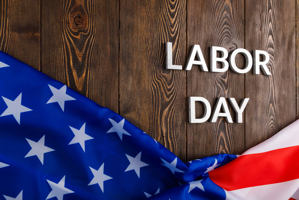 words labor day laid with silver metal letters on wooden surface with crumpled USA flag on bottom side - Fotoğraf, Görsel