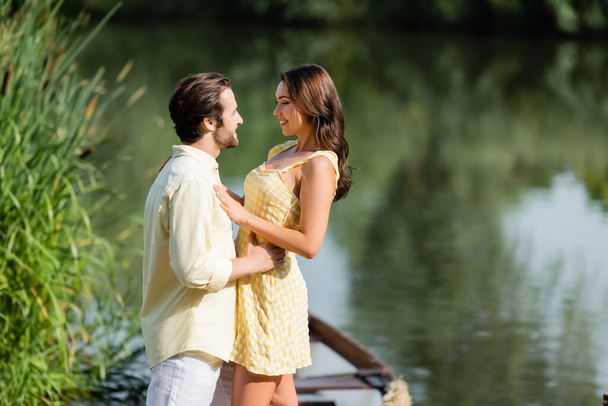 feliz joven pareja mirando el uno al otro cerca del lago - Foto, imagen