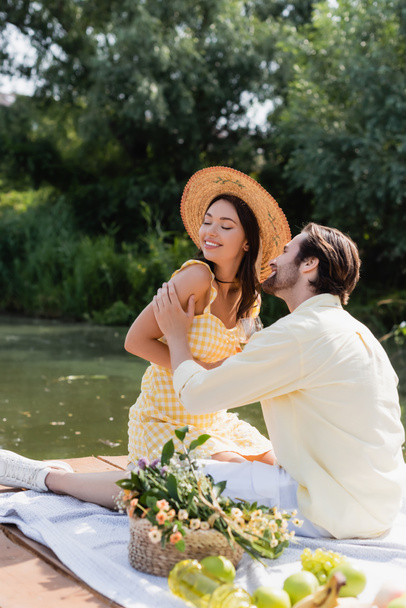 couple romantique souriant pendant le pique-nique sur la jetée près du lac - Photo, image