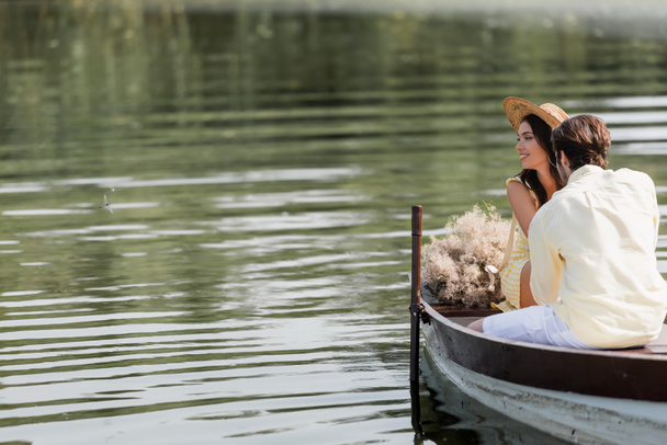 hymyilevä nainen olkihattu katselee pois lähellä romanttinen poikaystävä aikana vene ratsastaa - Valokuva, kuva