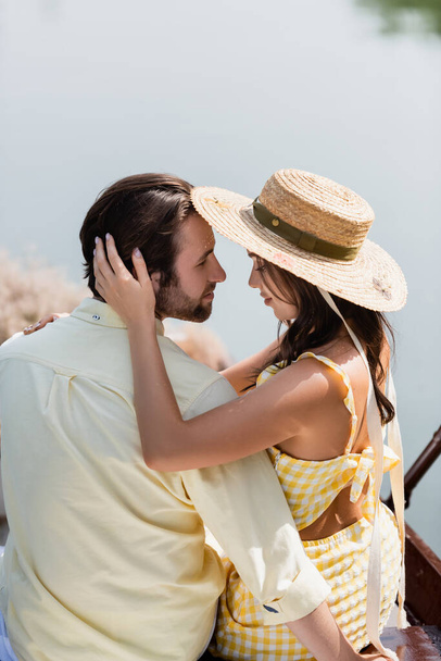smiling young woman in sun hat hugging man - 写真・画像