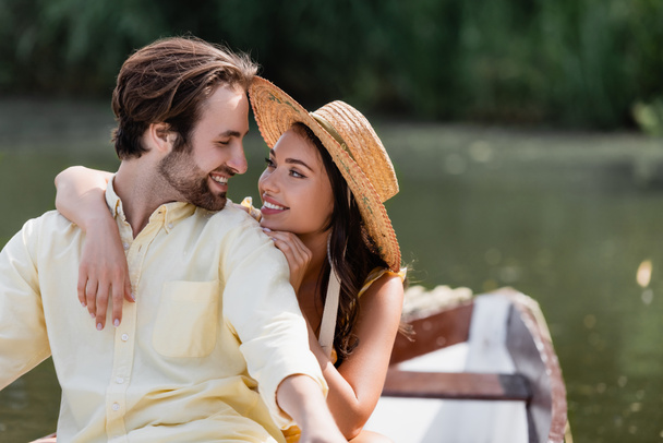 smiling young woman in straw hat hugging happy man during romantic boat trip  - Photo, Image