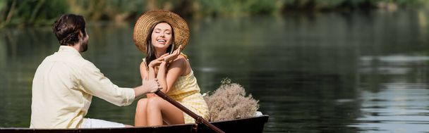 femme souriante en chapeau de paille ayant romantique promenade en bateau avec l'homme, bannière - Photo, image