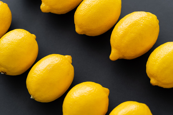 Top view of fresh lemons in rows on black background  - Foto, Bild