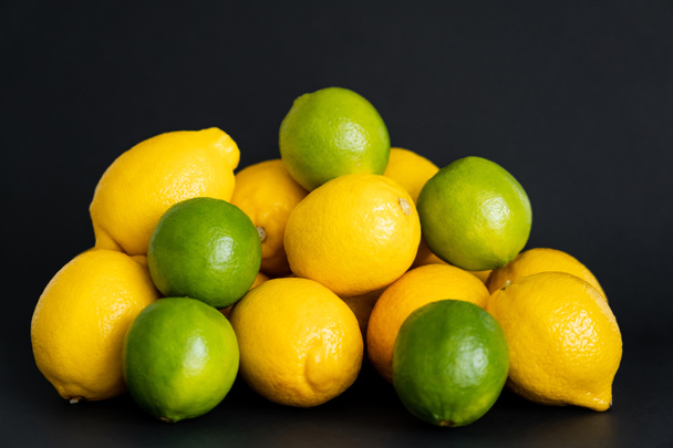 Fresh limes near lemons on black background  - Foto, afbeelding