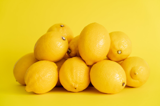 Heap of fresh lemons on yellow surface  - Foto, imagen