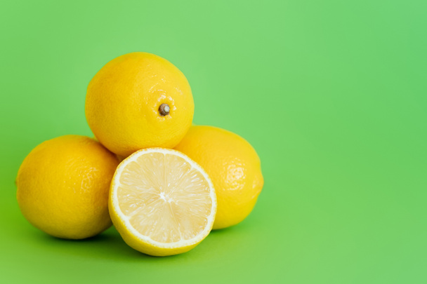 Half of juicy lemon on green surface with copy space - Foto, imagen