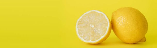 Крупним планом вид соковитої половини і цілого лимона на жовтому фоні, банер
  - Фото, зображення