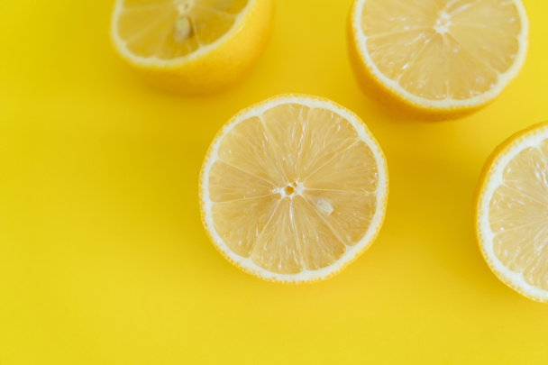 Top view of halves of lemons on yellow background  - 写真・画像