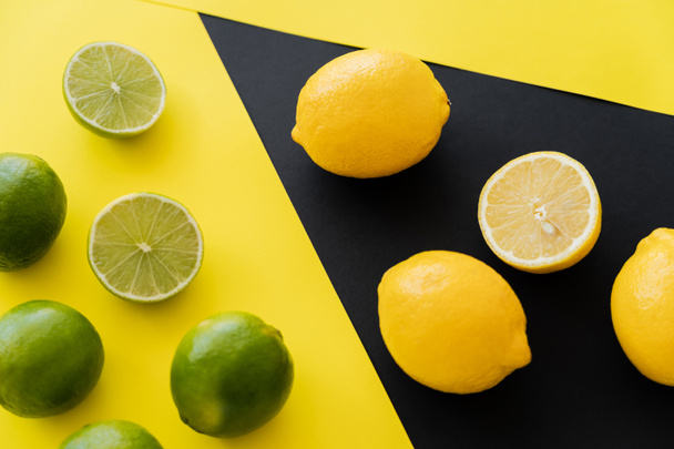 Top view of fresh limes and lemons on black and yellow background - Foto, afbeelding