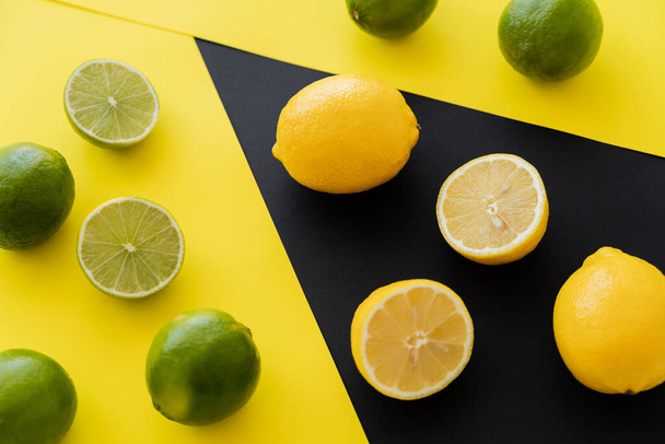 Top view of fresh lemons on black and limes on yellow background - Fotó, kép