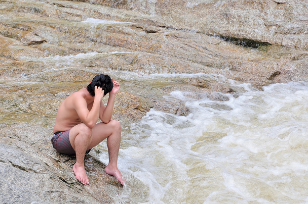 Hombre deprimido sentado en las rocas
 - Foto, imagen