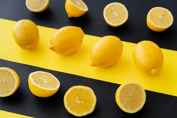 Flat lay of organic lemons on black and yellow background - Foto, afbeelding