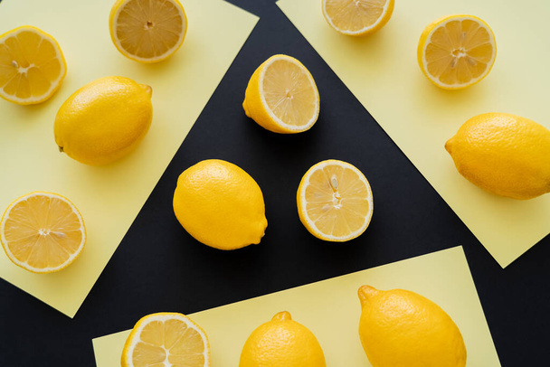 Flat lay with bright lemons on beige and black background  - Photo, image