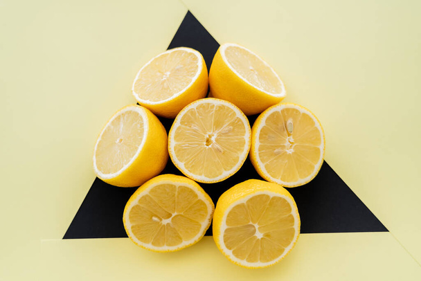 Вид зверху круглий з розрізаних лимонів на бежевому і чорному тлі
  - Фото, зображення