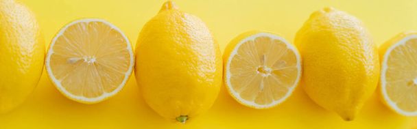 Flat lay with cut and whole lemons on yellow surface, banner  - Fotografie, Obrázek
