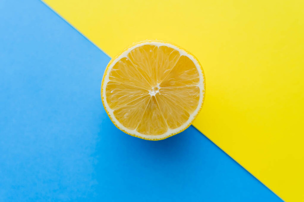 Top view of cut lemon on blue and yellow background - Foto, afbeelding