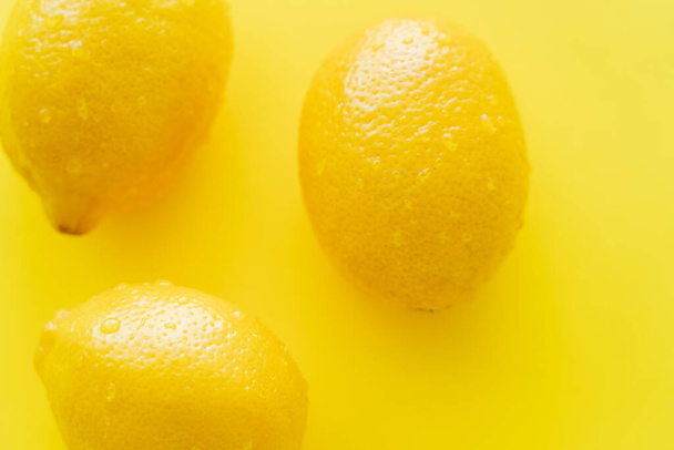 Top view of wet lemons on yellow background  - Zdjęcie, obraz