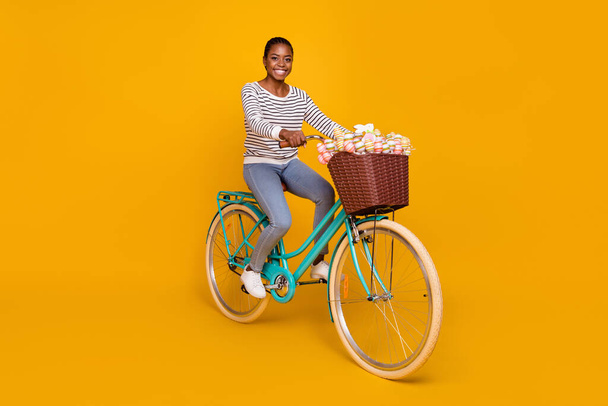 Full size profile side photo of young cheerful girl ride bicycle colorful eggs stick weekend isolated over yellow color background - Fotoğraf, Görsel