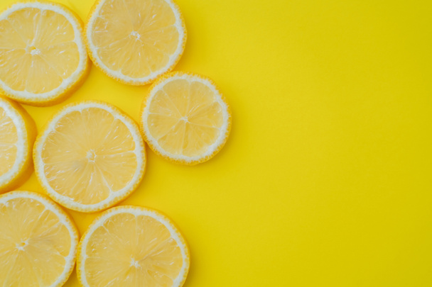 Top view of sliced lemon on yellow background with copy space - Foto, afbeelding