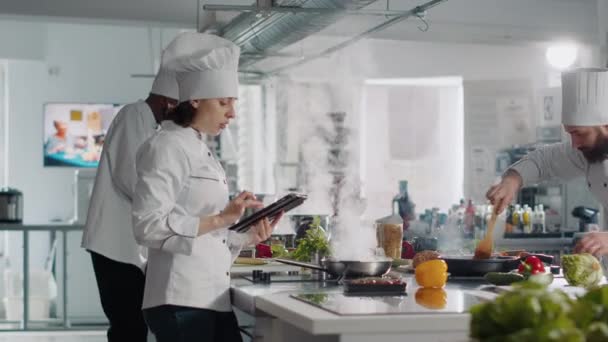 Female chef cooking culinary food recipe from digital tablet - Footage, Video