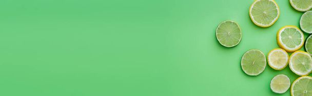 Κάτοψη φέτες φρέσκων λεμονιών και γλυκολέμονων σε πράσινο φόντο, banner  - Φωτογραφία, εικόνα