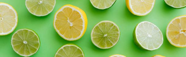 Draufsicht auf frische Zitronen- und Limonenhälften auf grünem Hintergrund, Banner  - Foto, Bild