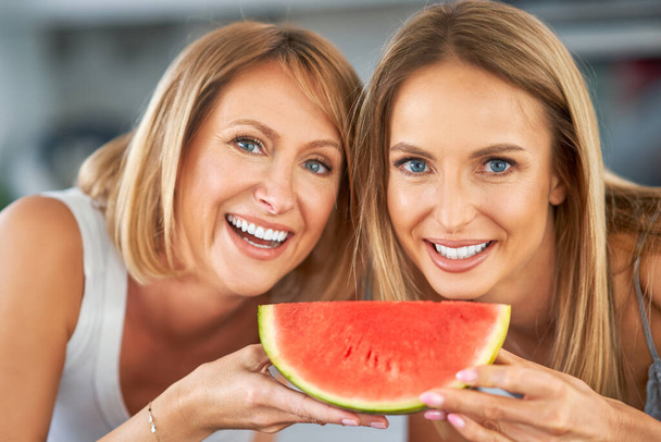 Leuke twee volwassen meisjes in de keuken met watermeloen - Foto, afbeelding