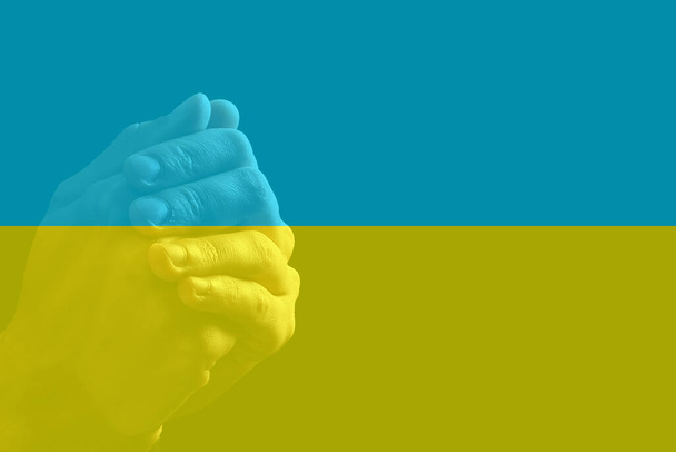 Προσευχήσου για την Ουκρανία. χέρι στην προσευχή και την ουκρανική σημαία στο παρασκήνιο. - Φωτογραφία, εικόνα