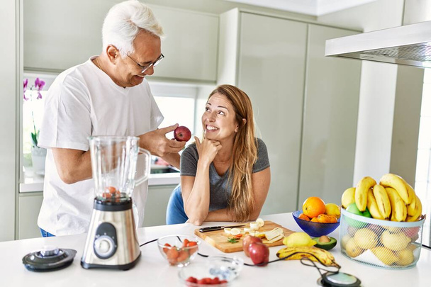 Middle age hispanic couple smiling happy cooking smoothie at the kitchen. - Foto, Bild