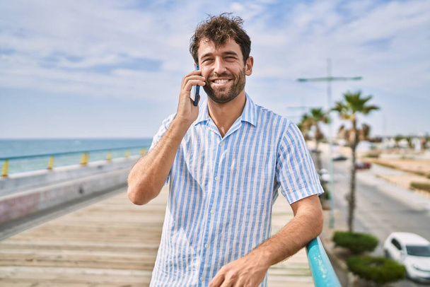 Young hispanic man smiling happy talking on the smartphone at the promenade. - Foto, Imagen