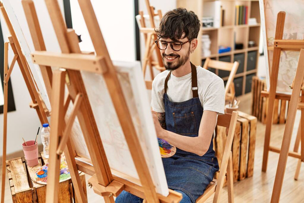 Молодий іспаномовний художник посміхається щасливим малюнком в художній студії
. - Фото, зображення