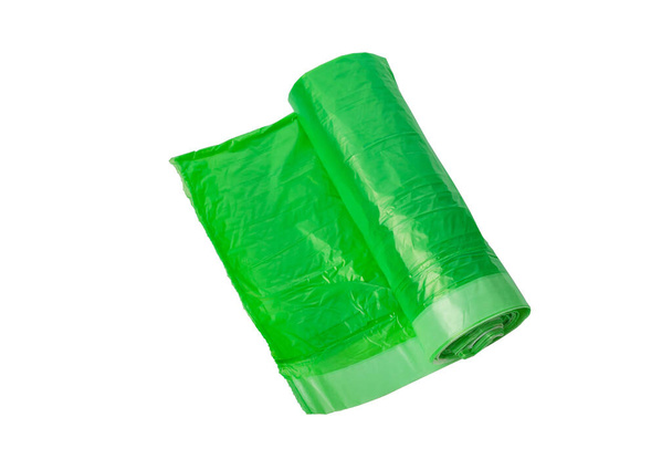 Rotolo di sacchetti di plastica per rifiuti domestici. Spazzatura e sacchetti della spazzatura di colore verde su uno sfondo bianco isolato. - Foto, immagini