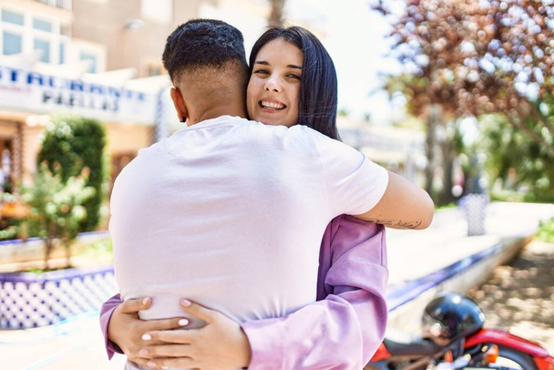 Jovem casal hispânico de namorado e namorada juntos ao ar livre em um dia ensolarado abraçando com amor - Foto, Imagem