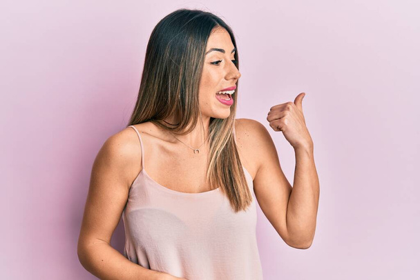 Nuori latino nainen yllään rento hihaton t paita osoittaa peukalo ylös puolelle hymyillen onnellinen suu auki  - Valokuva, kuva