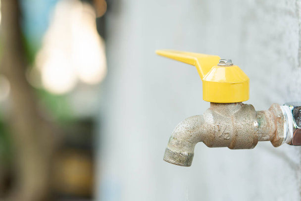 Wasserhahn mit einem Wassertropfen. Alter gelber Wasserhahn  - Foto, Bild