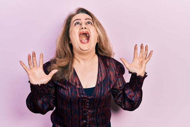 Middle age caucasian woman wearing casual clothes crazy and mad shouting and yelling with aggressive expression and arms raised. frustration concept.  - Foto, Imagem