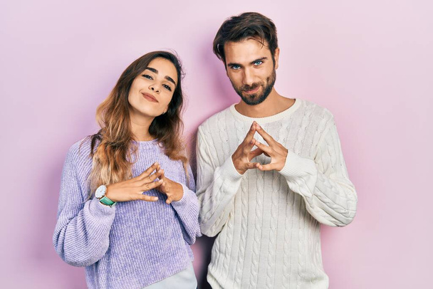 Young hispanic couple wearing casual clothes hands together and fingers crossed smiling relaxed and cheerful. success and optimistic  - Foto, Bild