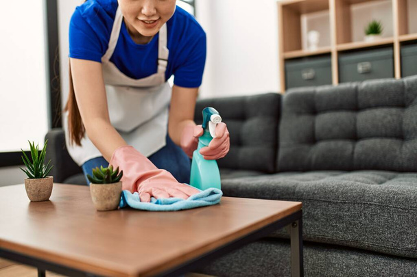 Tavolo di pulizia della giovane casalinga cinese con diffusore e straccio a casa. - Foto, immagini