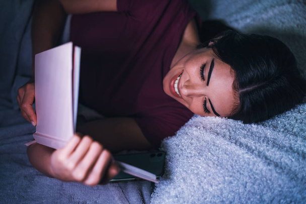 Young woman reading book in bed - Fotografie, Obrázek