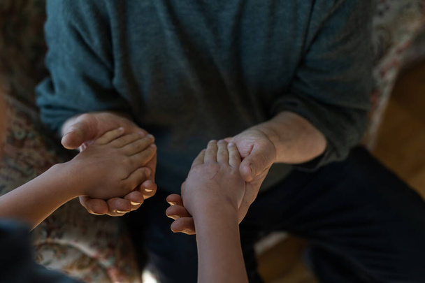 τα χέρια του παιδιού αγκαλιάζοντας το χέρι του γέρου - Φωτογραφία, εικόνα