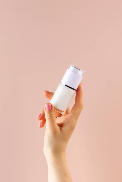 A mock-up of a jar of moisturizer in a womans hand on a pink background. - Foto, Imagen