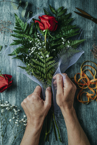 カタルーニャ語で「聖ジョージの日」を意味するサンジョルディの赤いバラの花束を並べ男の高い角度ビュー,カタルーニャの赤いバラを与えるために伝統であるとき,灰色の素朴なテーブルの上に - 写真・画像