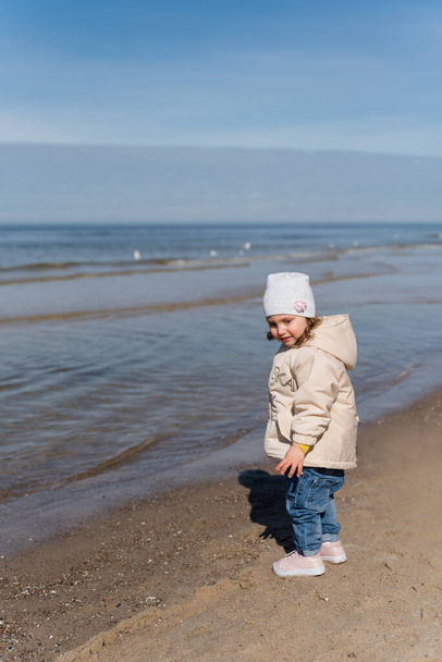 gyermek anya játszik a tengerparton hideg időben.. - Fotó, kép